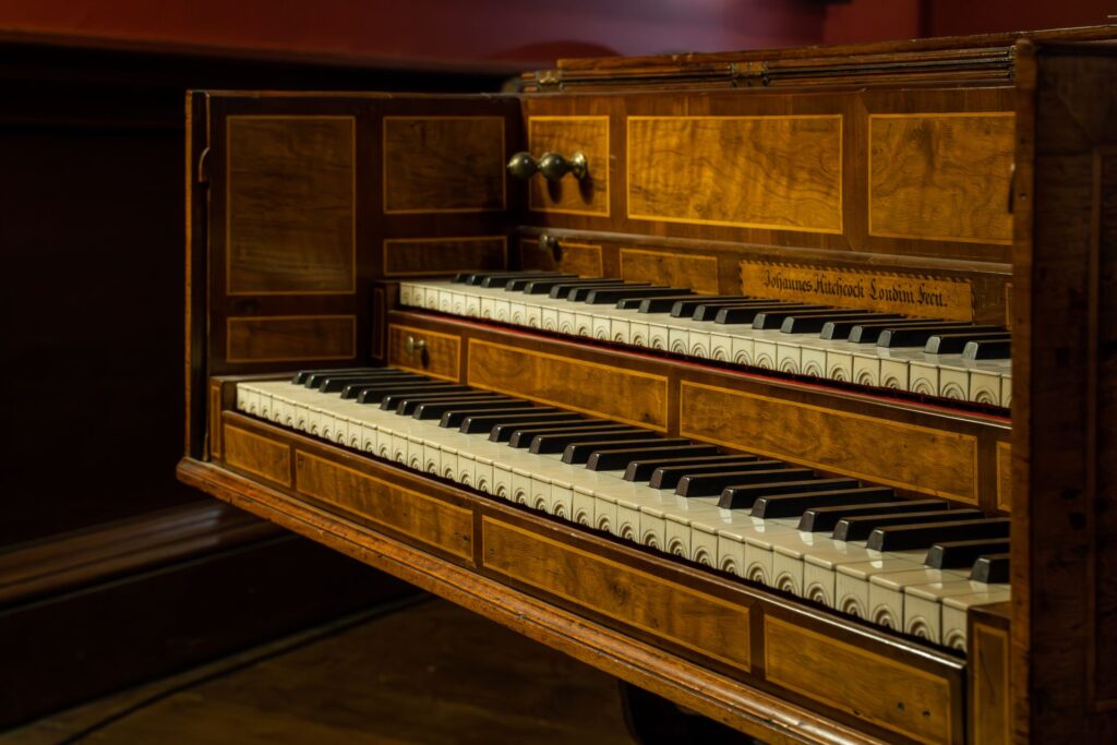 Close-up of an antique wooden keyboard instrument, a harpsichord with intricate designs.