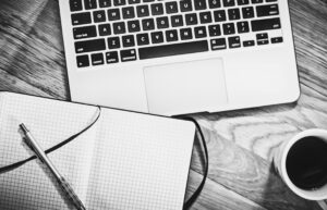 Notebook, laptop, pen and coffee on a desk ready for writing