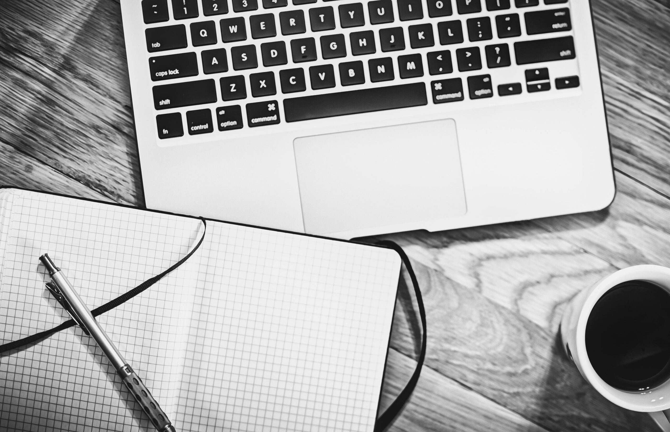 Notebook, laptop, pen and coffee on a desk ready for writing