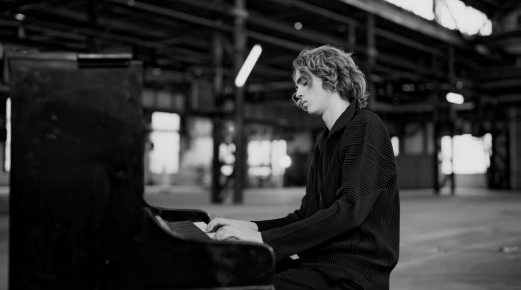 Pianist performing on a black upright piano inside an abandoned factory in black and white picture. Justus Eichhorn Reimagines Schubert’s ‘Ständchen’