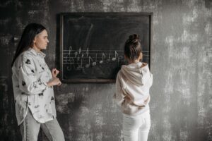 A mother instructs her daughter in music notation at a blackboard, fostering learning.