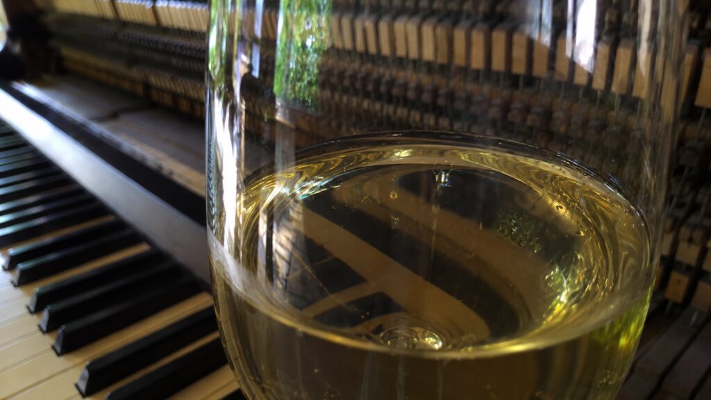 A drink glass in front of a piano with hammer actions and claviers. The Sound of Tasting Series Tunitemusic